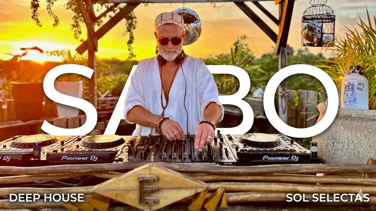 DJ playing a sunset set on Pioneer decks in a wooden booth in Tulum, filmed by Ephimera